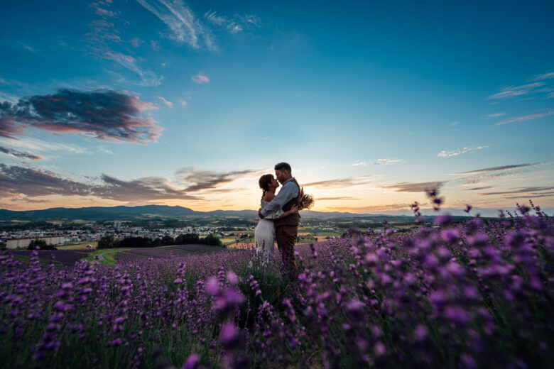 夕暮れのラベンダー園で抱き合う新郎新婦